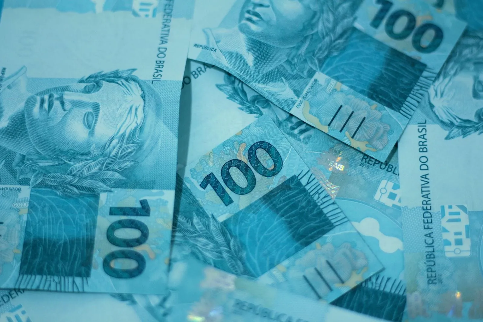 Notas de 100 reais espalhadas, vistas de perto