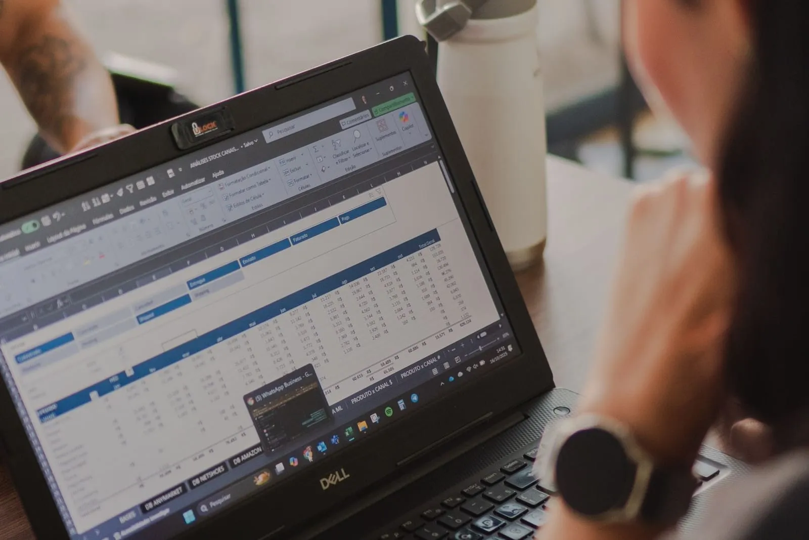 Notebook aberto com uma planilha de resultados, visto por cima do ombro de quem analisa